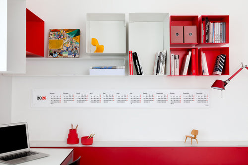 Modern office desk with red and white shelves, Octàgon Design calendar, and mini design icons chairs.