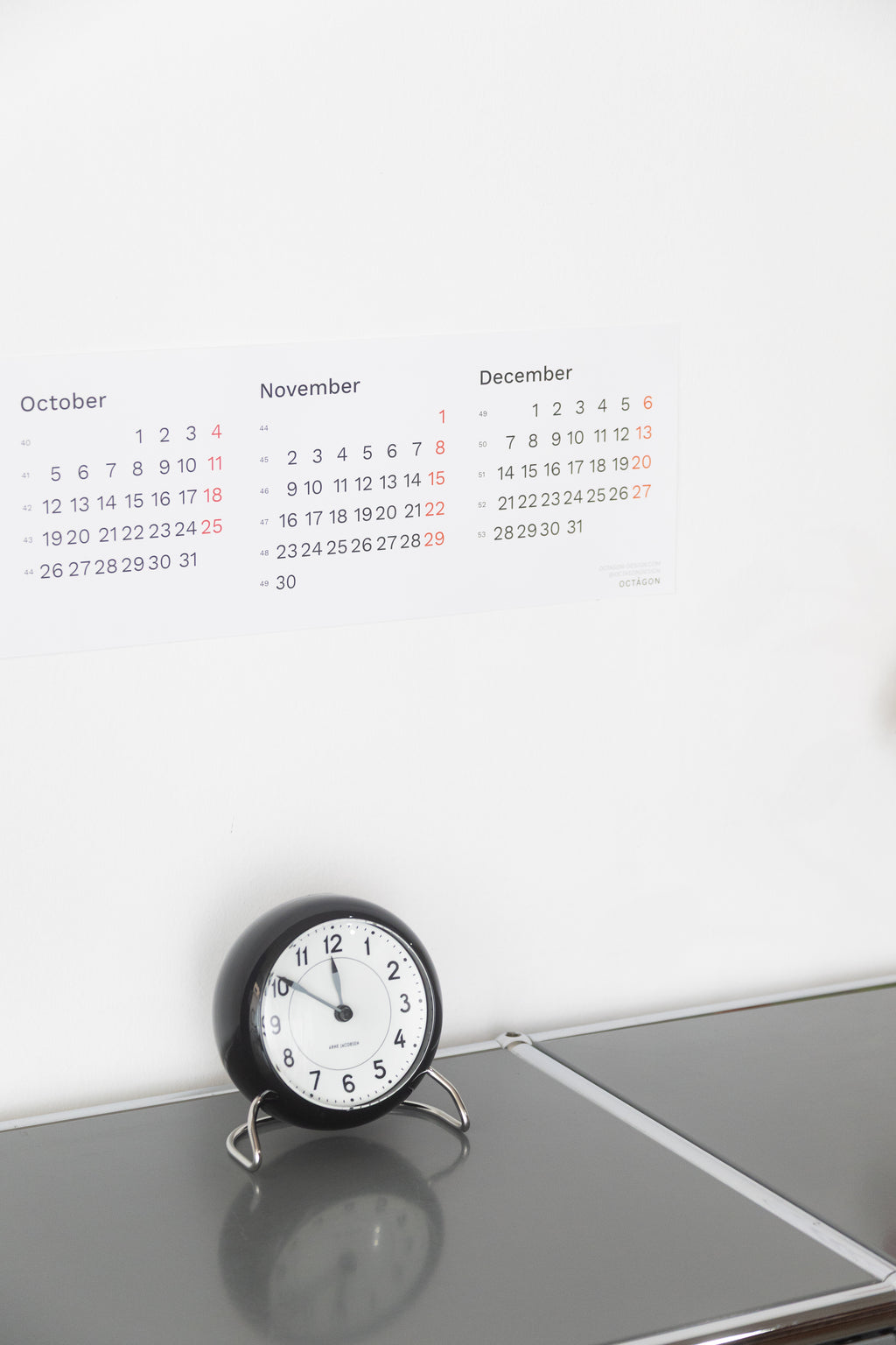 2027 Horizontal Calendar by Octàgon Design. The calendar placed on top of a piece of USM furniture and besides the Arne Jacobsen clock