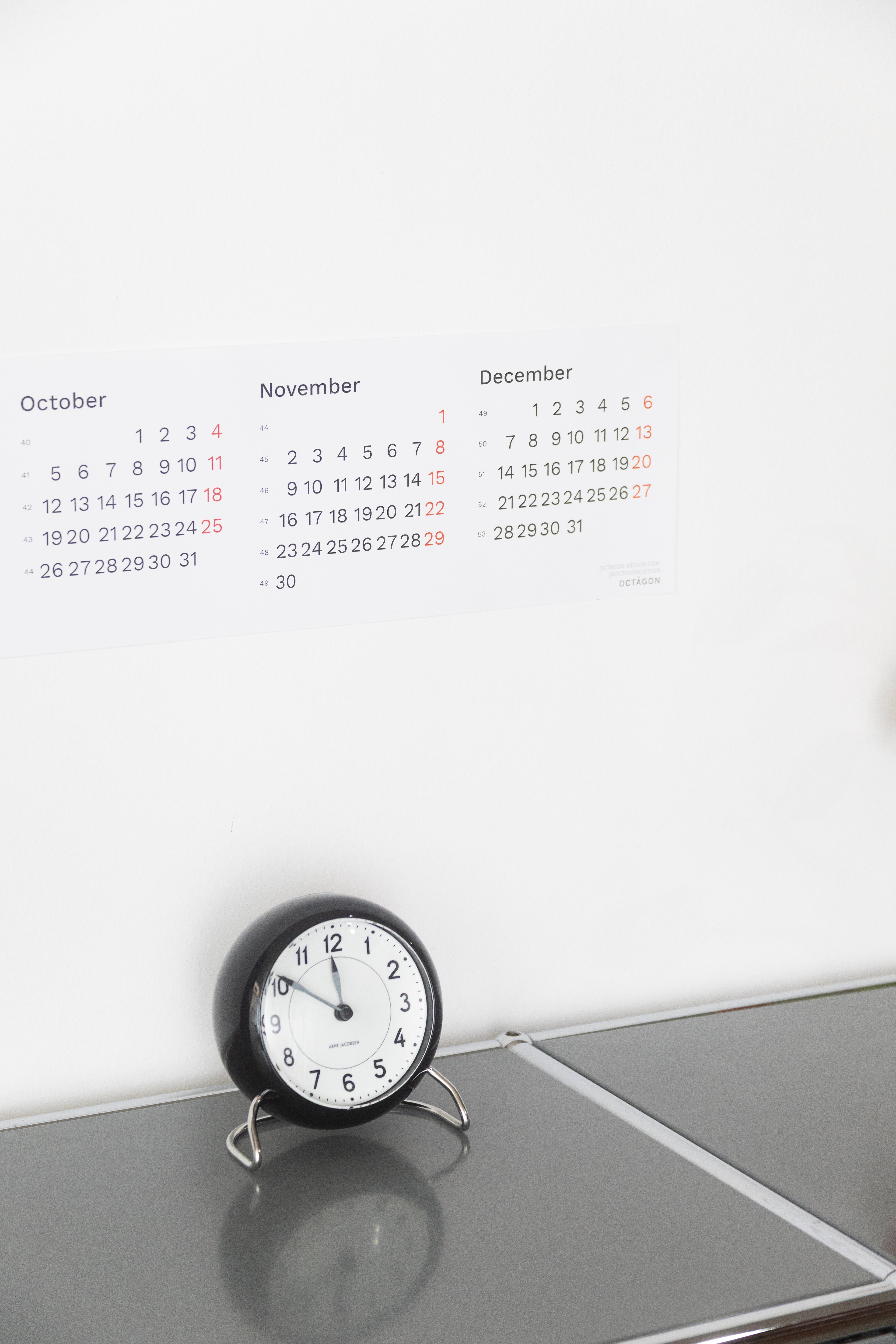 2027 Horizontal Calendar by Octàgon Design. The calendar placed on top of a piece of USM furniture and besides the Arne Jacobsen clock