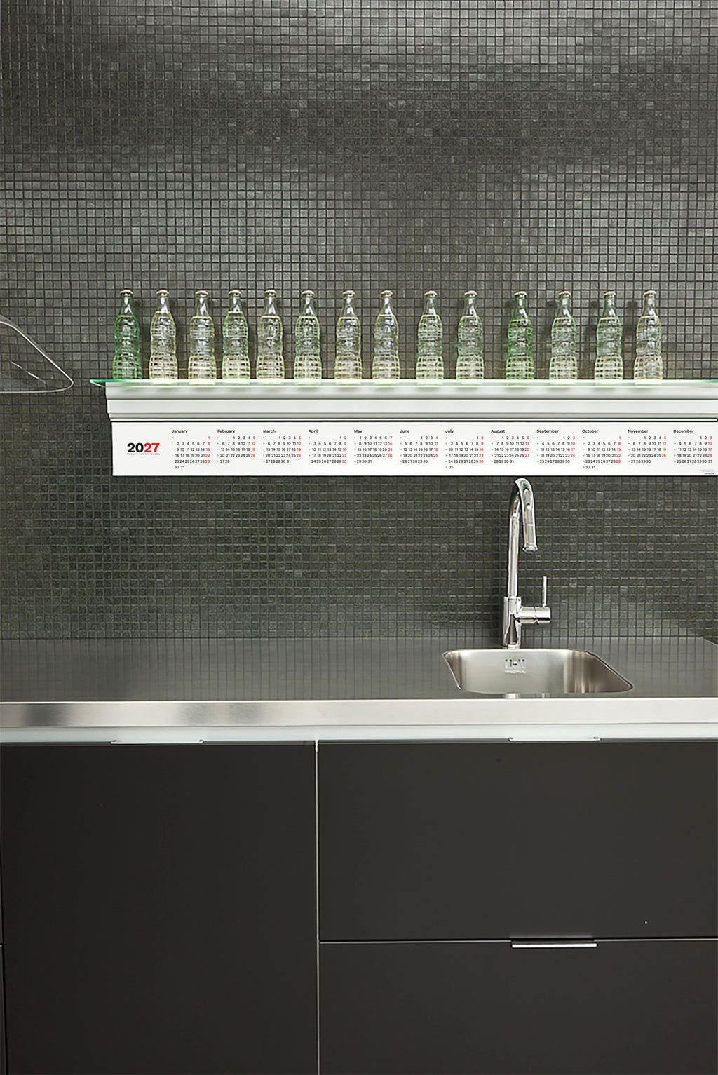 2027 Horizontal Calendar by Octàgon Design. The calendar placed under a bookshelf of a Boffi kitchen.