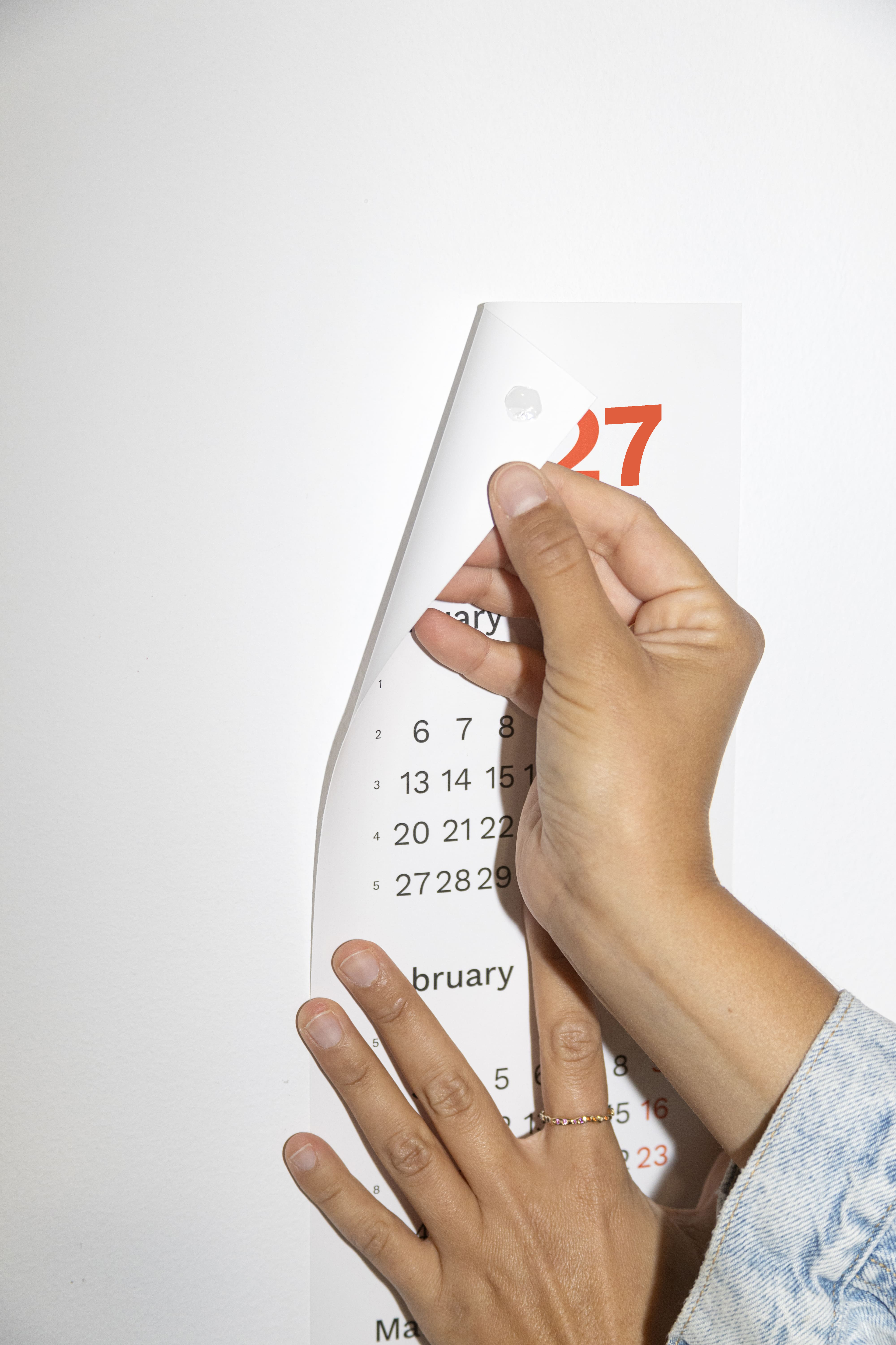 2027 Vertical Calendar by Octàgon Design. A girl hanging the calendar on the wall. 