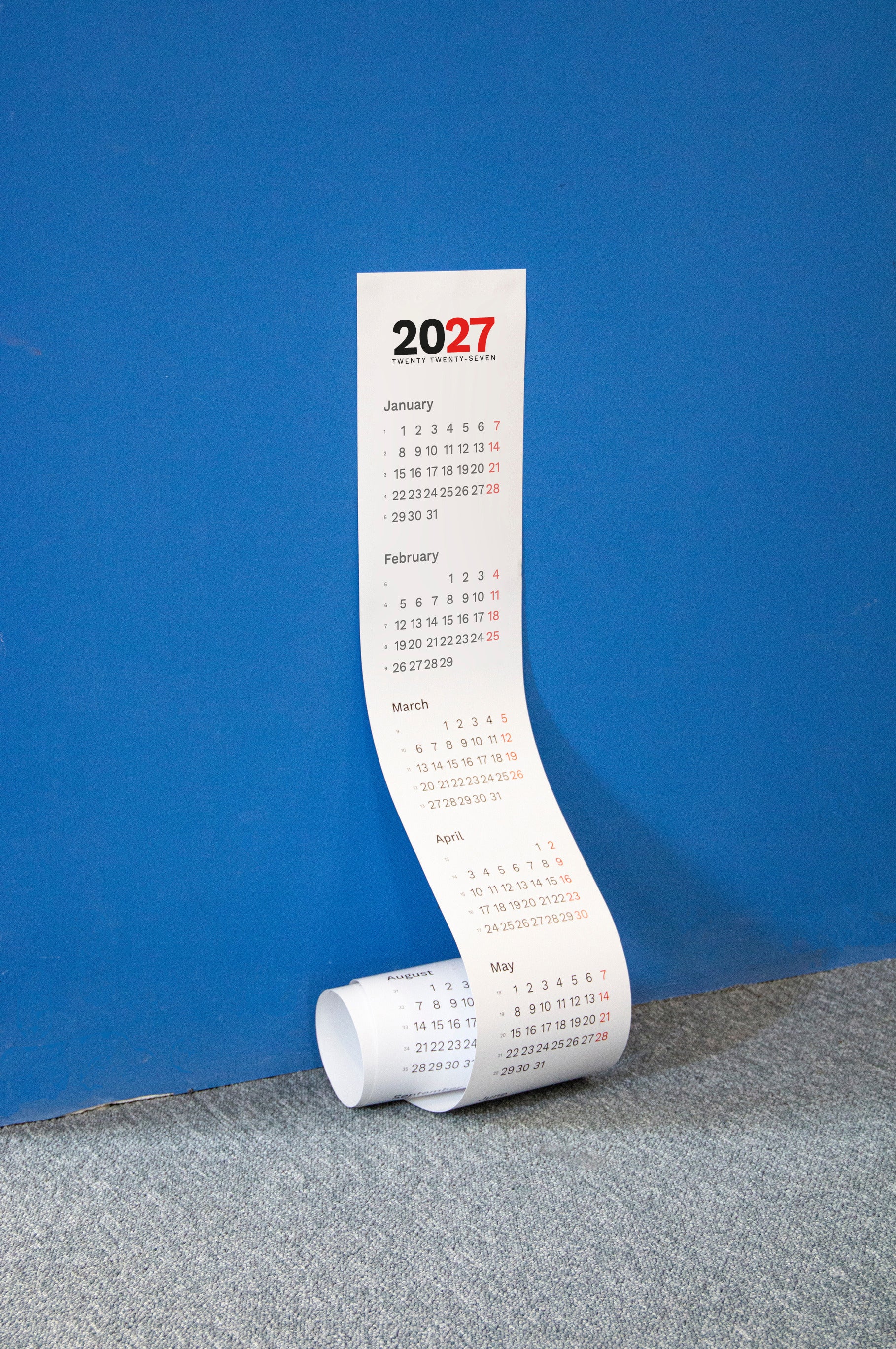 2027 Vertical Calendar by Octàgon Design. The calendar hangin on a blue wall.