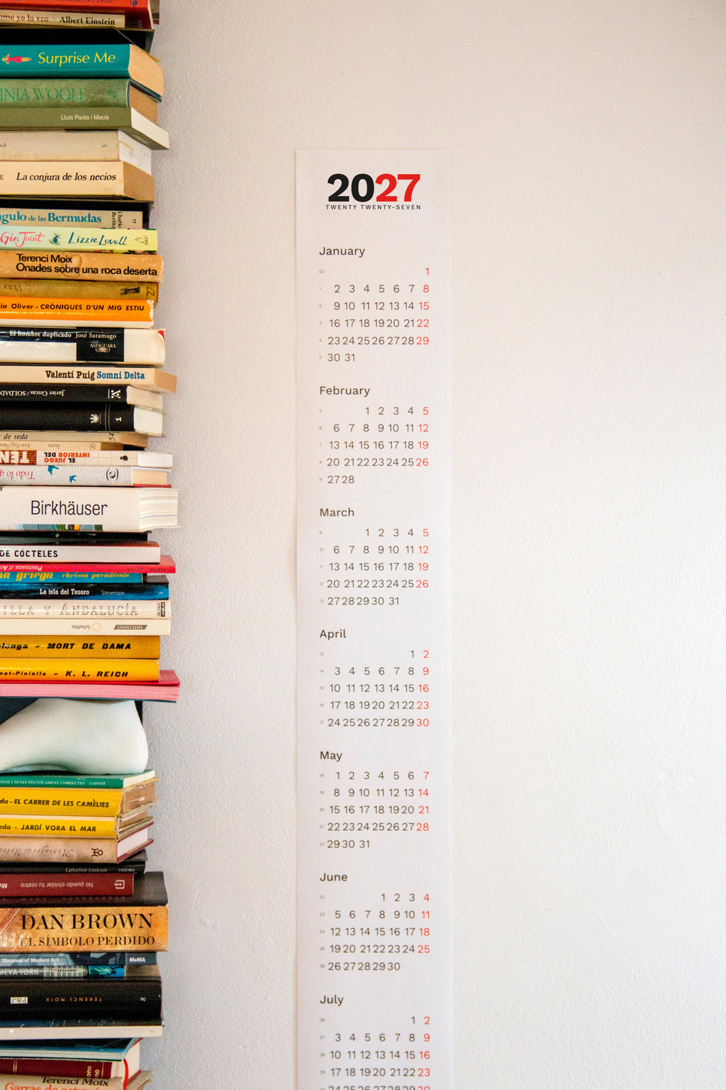 2027 Vertical Calendar by Octàgon Design. The calendar hanging on a wall beside a ptolomeo shelf.