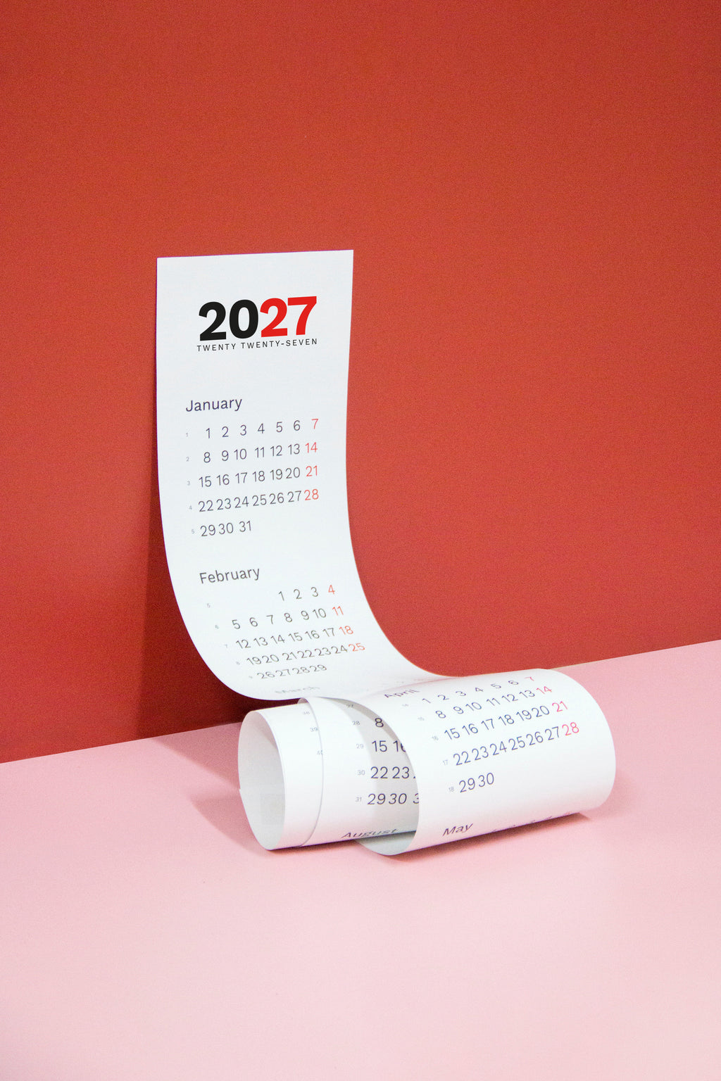 2027 Vertical Calendar by Octàgon Design. The calendar hanging on a red wall.