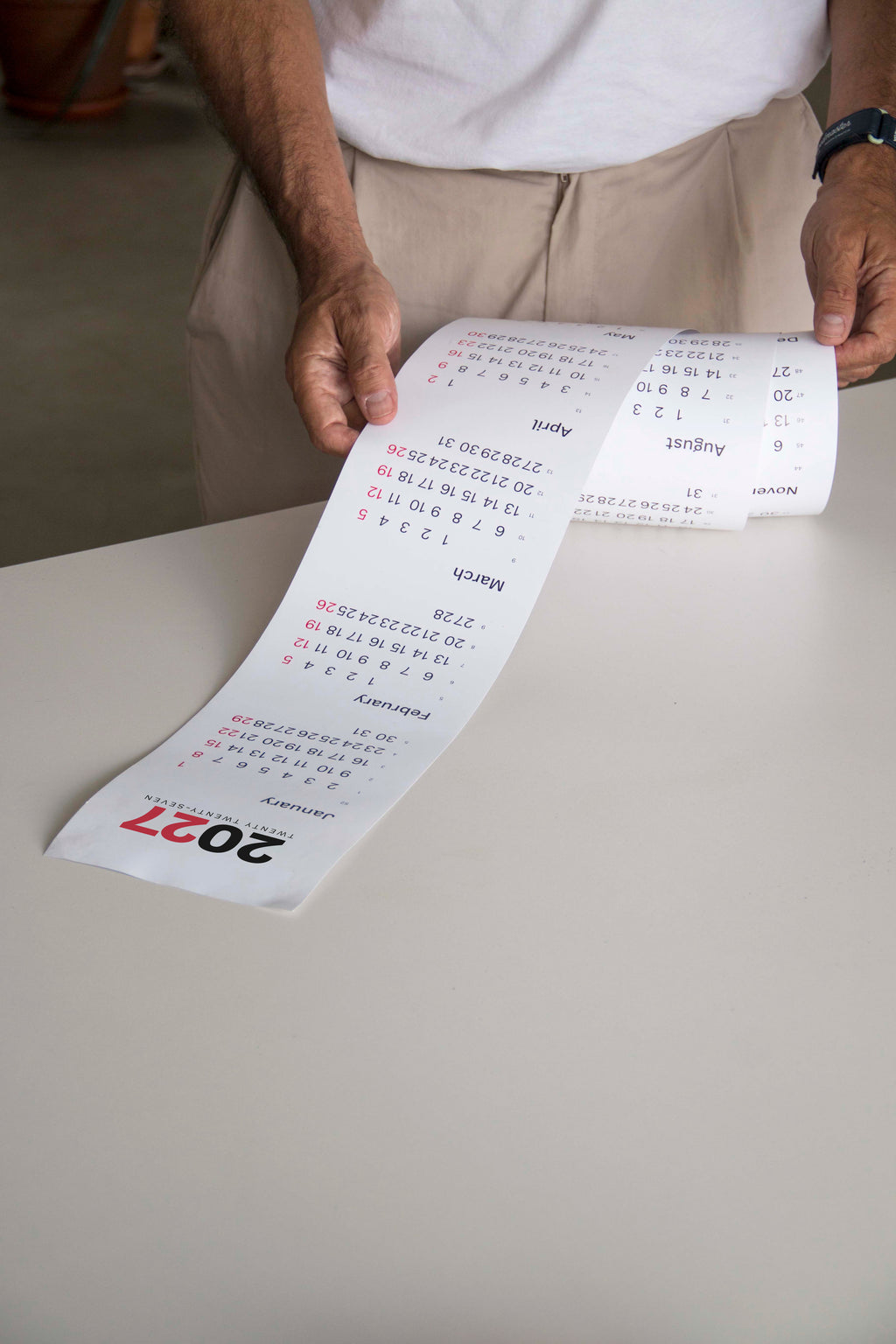 2027 Vertical Calendar by Octàgon Design. A man with the calendar in his hands.