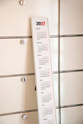 2027 Vertical Calendar by Octàgon Design. The framed calendar leaning on a USM piece of furniture.