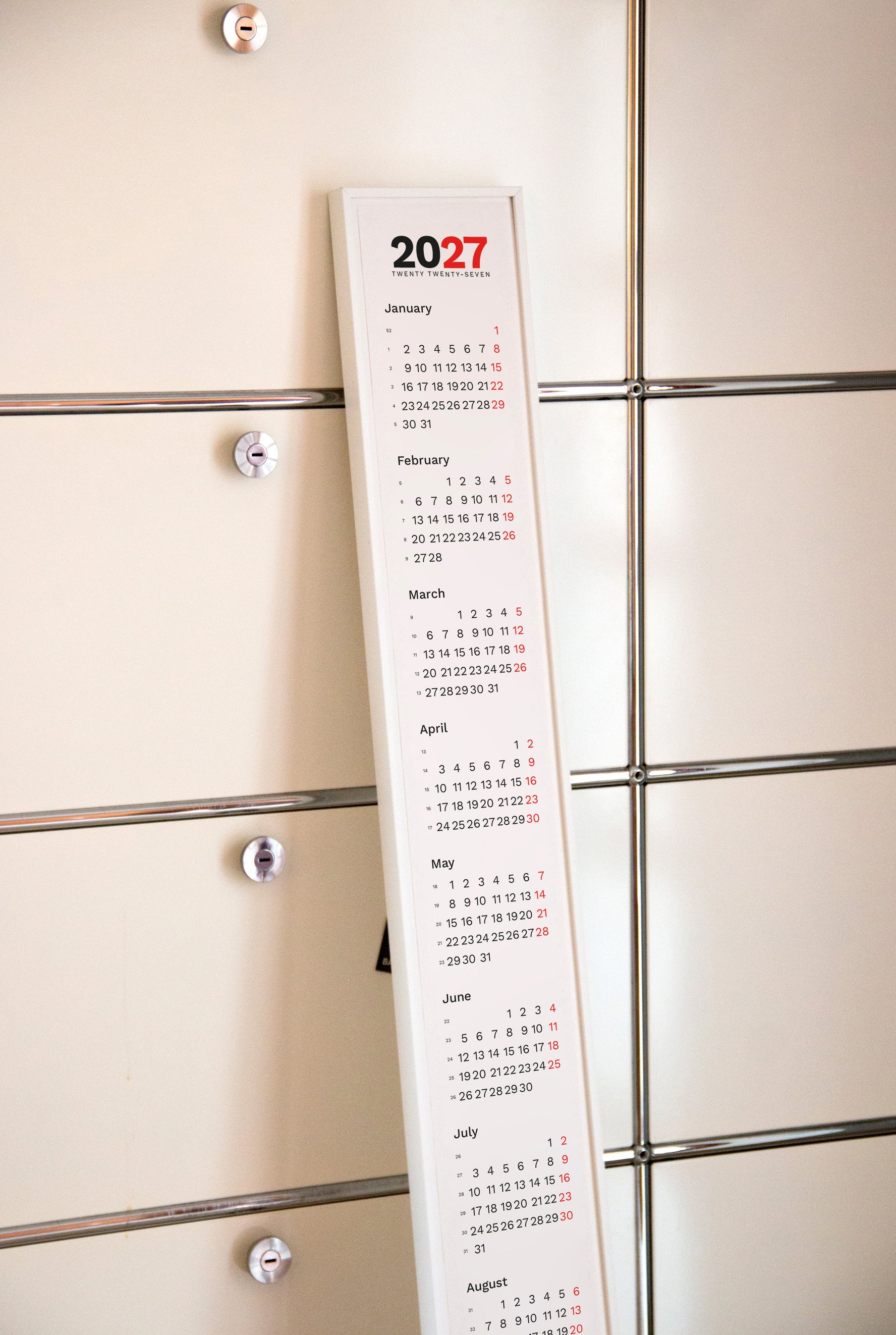 2027 Vertical Calendar by Octàgon Design. The framed calendar leaning on a USM piece of furniture.