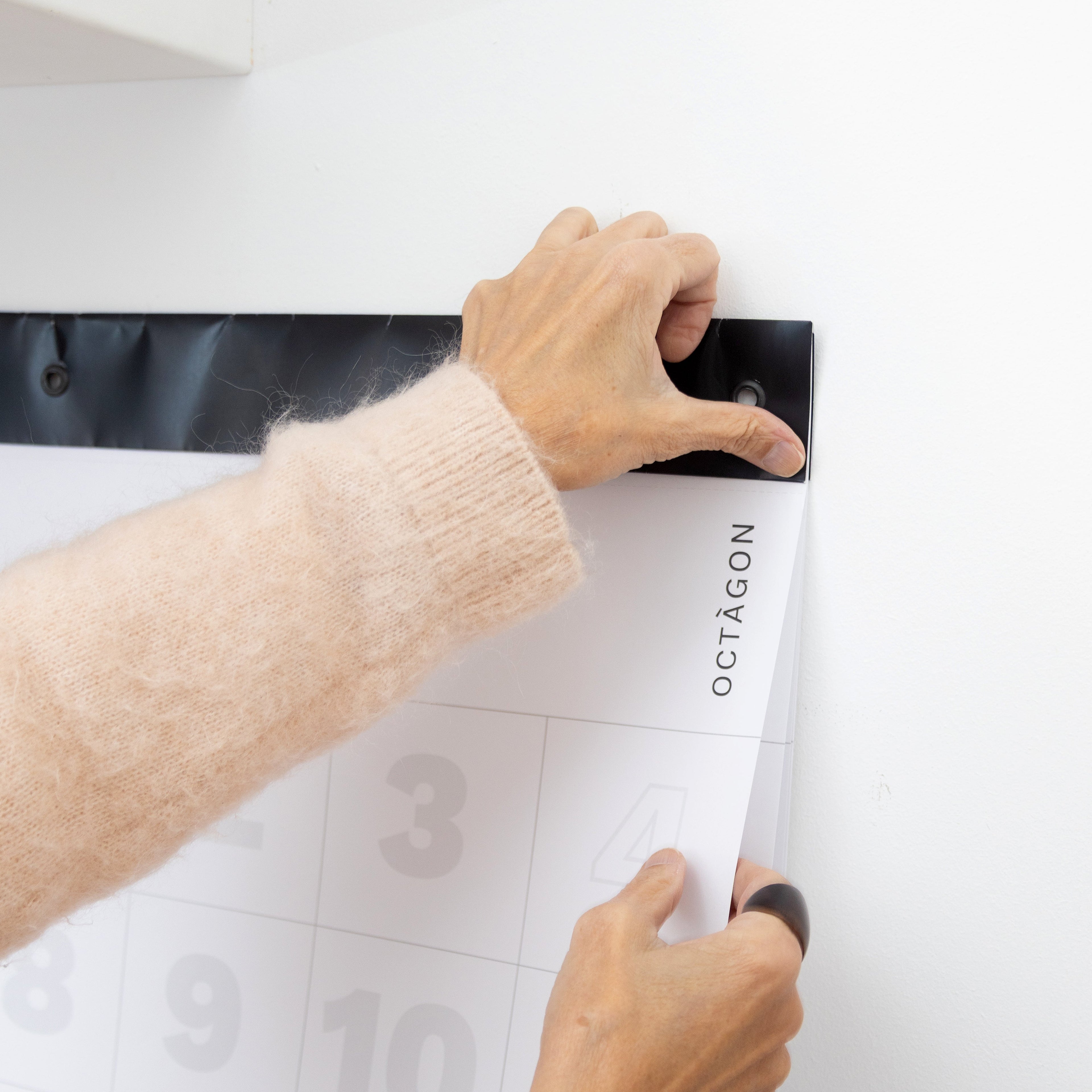 Hands easily tearing a page from a 2027 Octàgon Design giant wall calendar along its perforated line.
