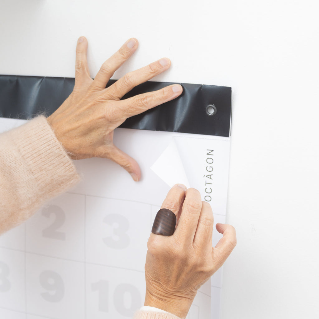 Hands easily tearing a page from a 2027 Octàgon Design giant wall calendar along its perforated line.