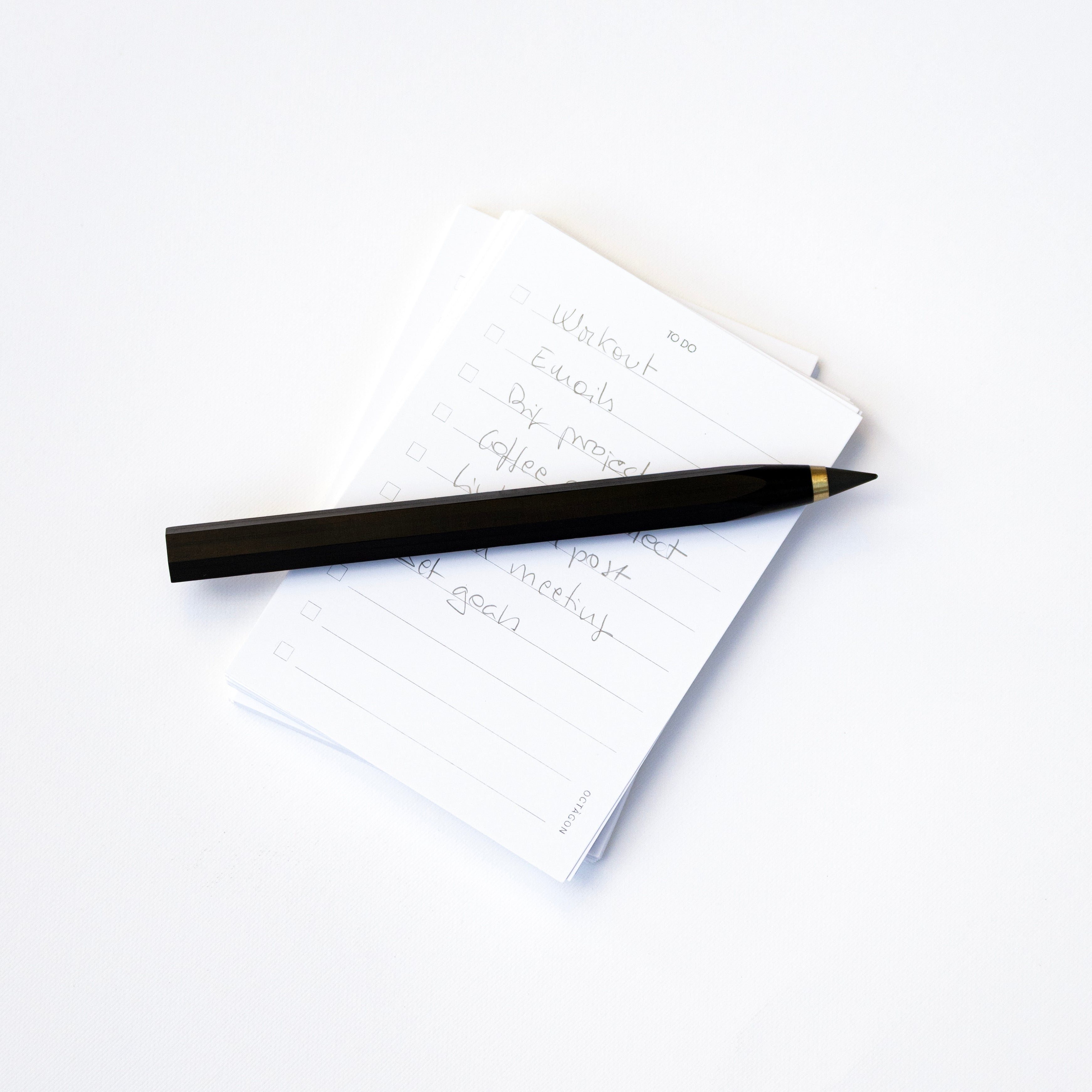 Octàgon Eternal Pencil on a white notepad with handwritten text on a white background