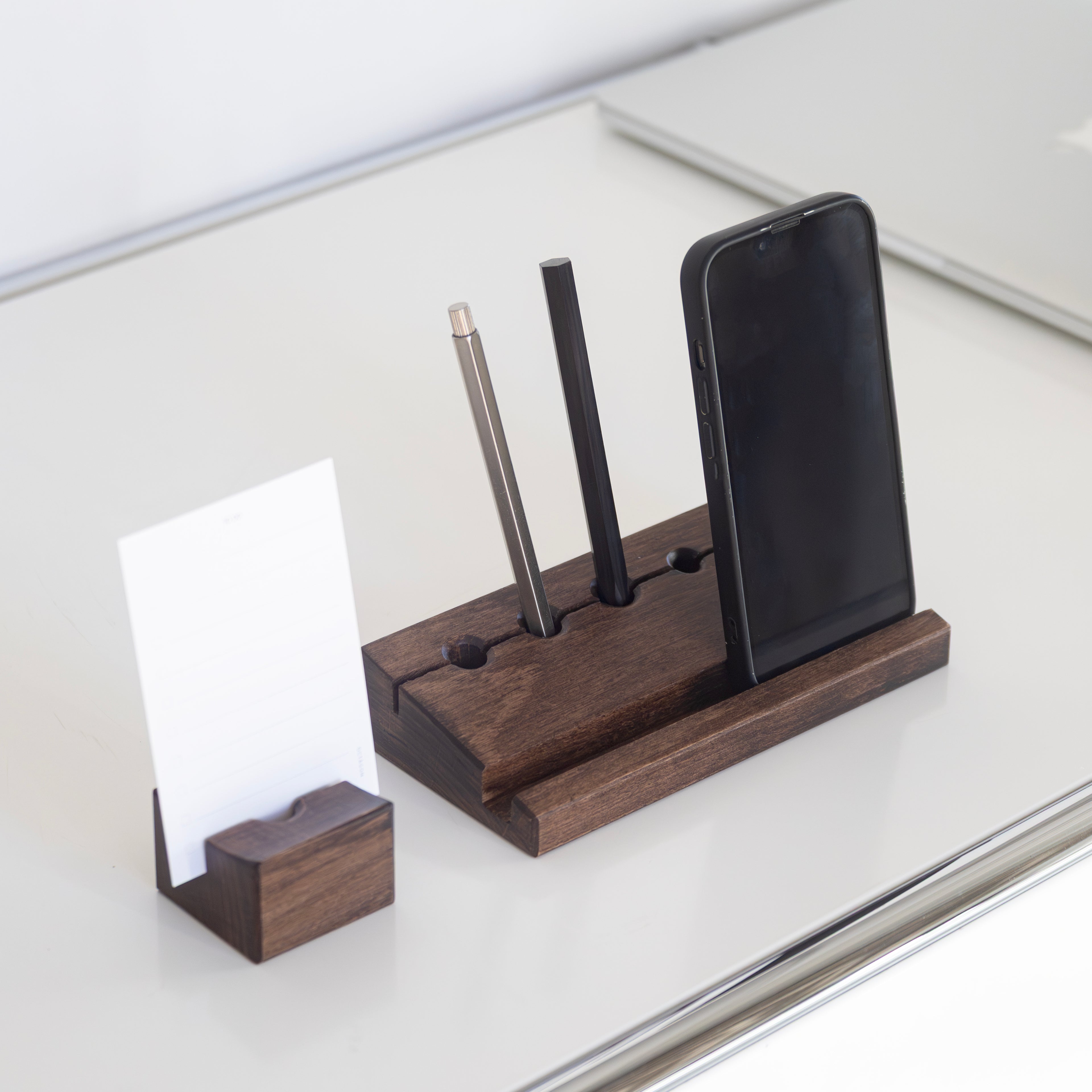 Min Point and Min Prism pencil holders with phone stand, and Min Cards on a reflective surface.  Octàgon Eternal Pencil