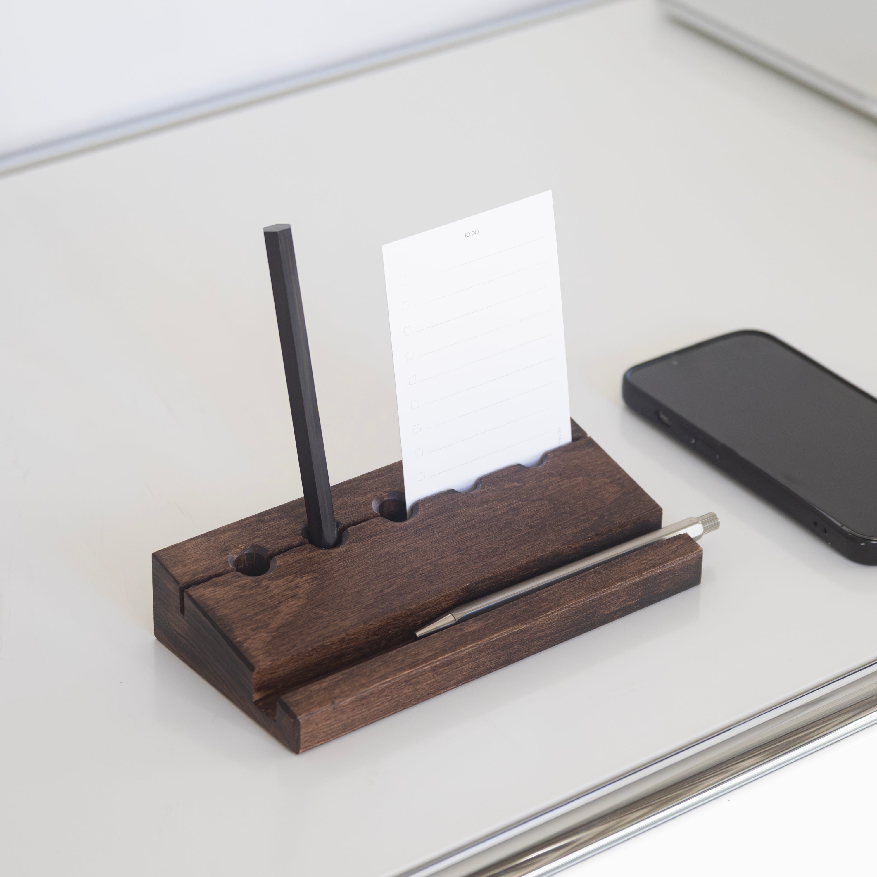 Min Prism wooden desk organizer with Octàgon Eternal Pencil, straw, and card on a white surface