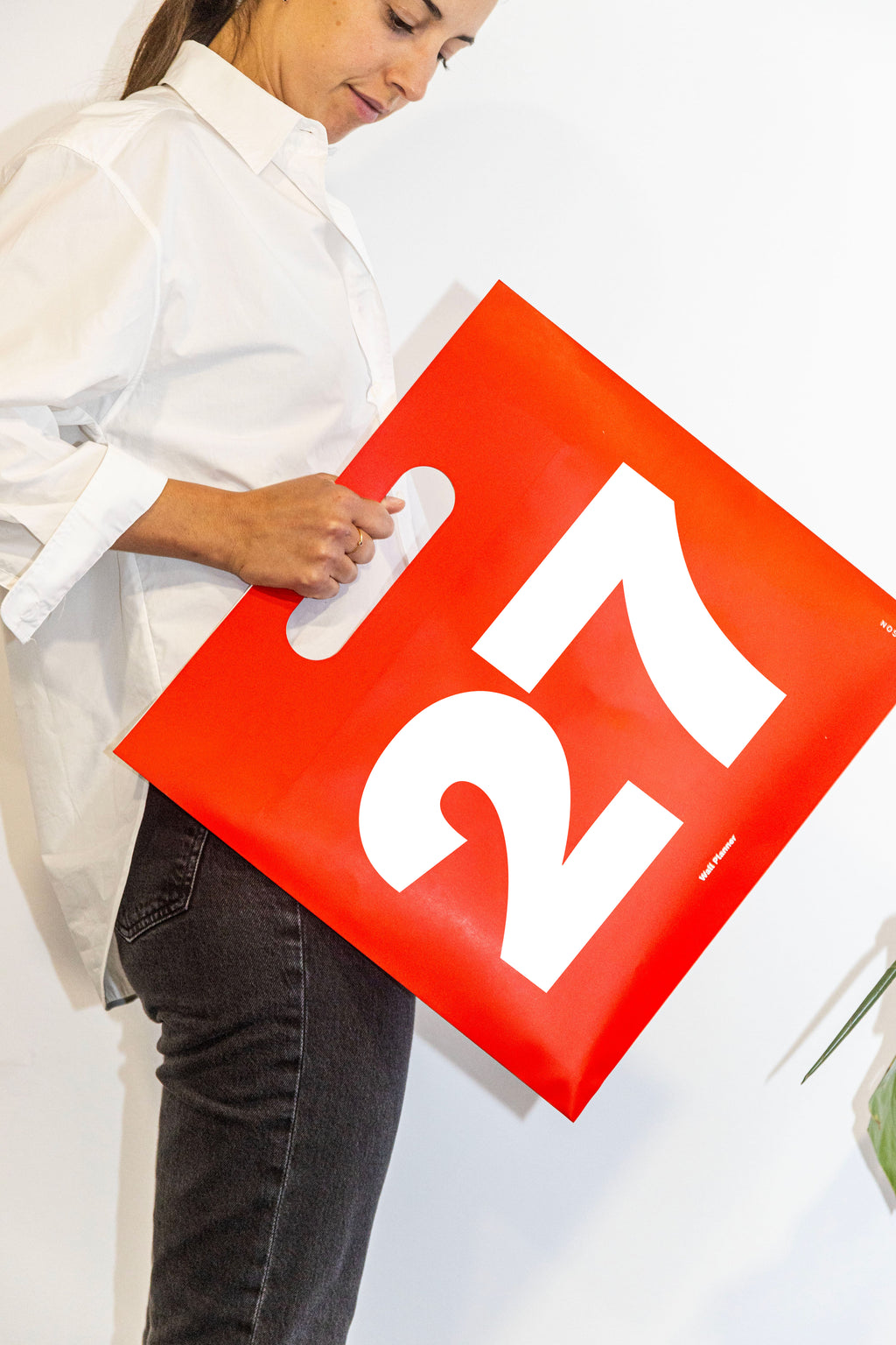 2027 Wall Planner by Octàgon Design. A girl showing the calendar and the bag.