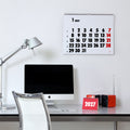 2027 Vinçon wall Calendar by Octàgon Design. The calendar holding on a white wall. Office atmosphere with the Tolomeo lamp, a Apple IMac and a Brionvega radio.