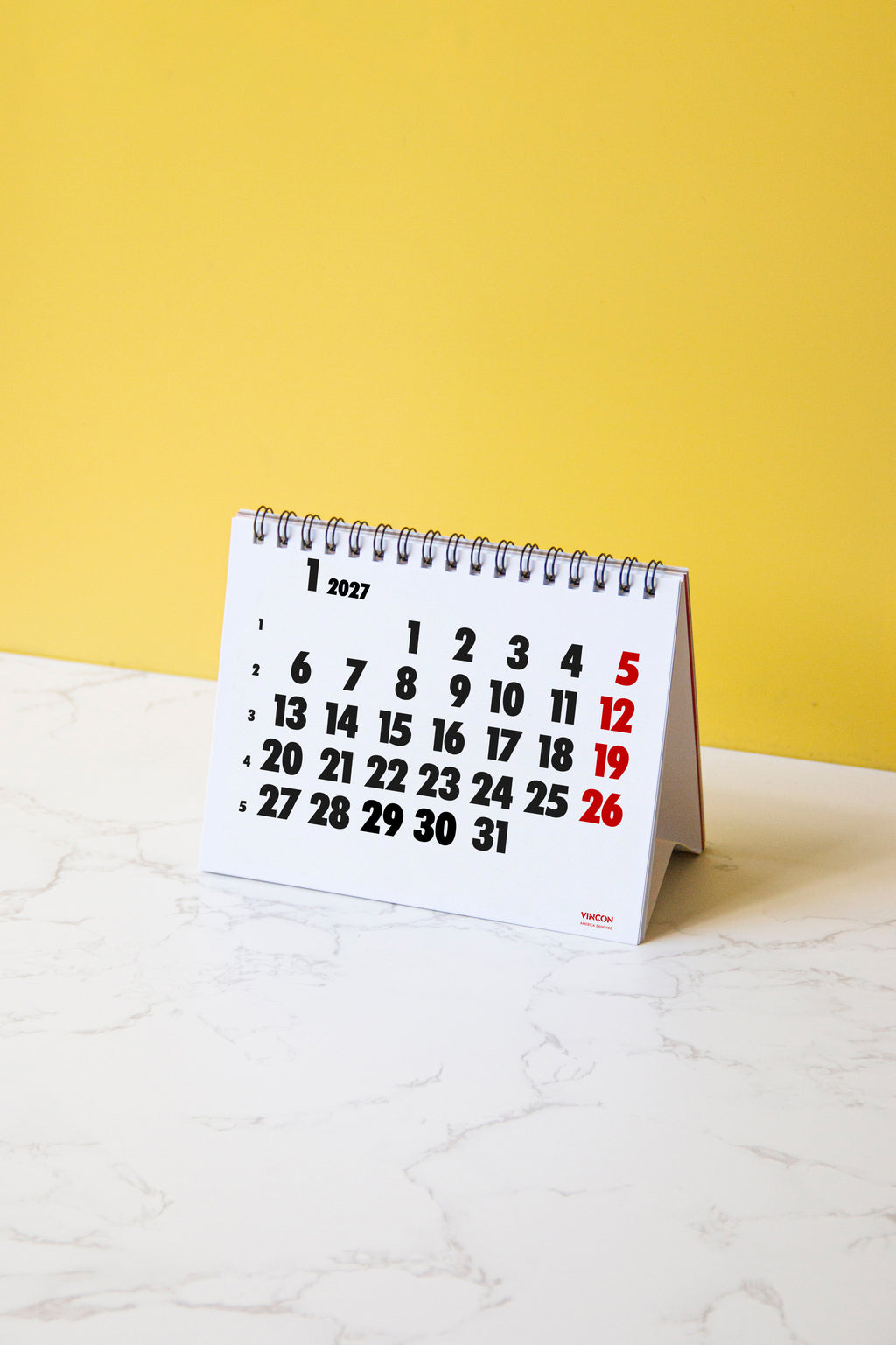 2027 Vinçon desk calendar by Octàgon Design. The calendar on a table.
