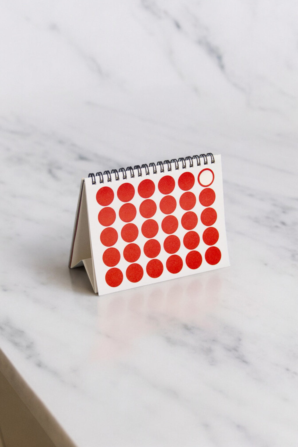 2027 Vinçon desk calendar by Octàgon Design. The calendar on a table showing the page of the date markers.