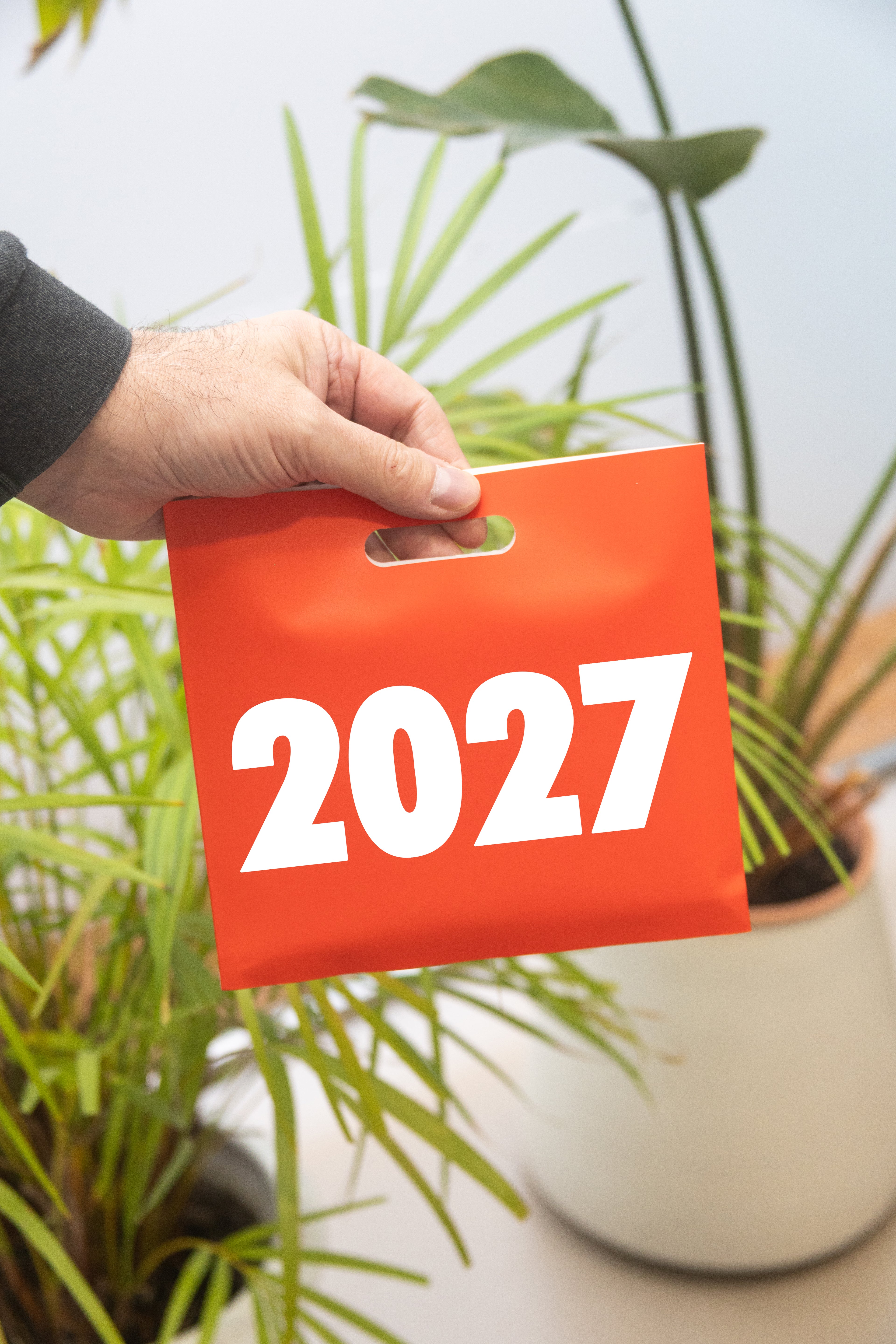 2027 Vinçon desk calendar by Octàgon Design. A man holding the calendar little bag.