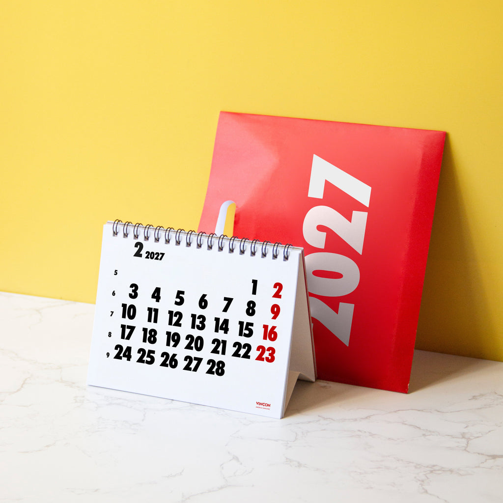 2027 Vinçon desk calendar by Octàgon Design. The calendar on a table showing the page of the February.