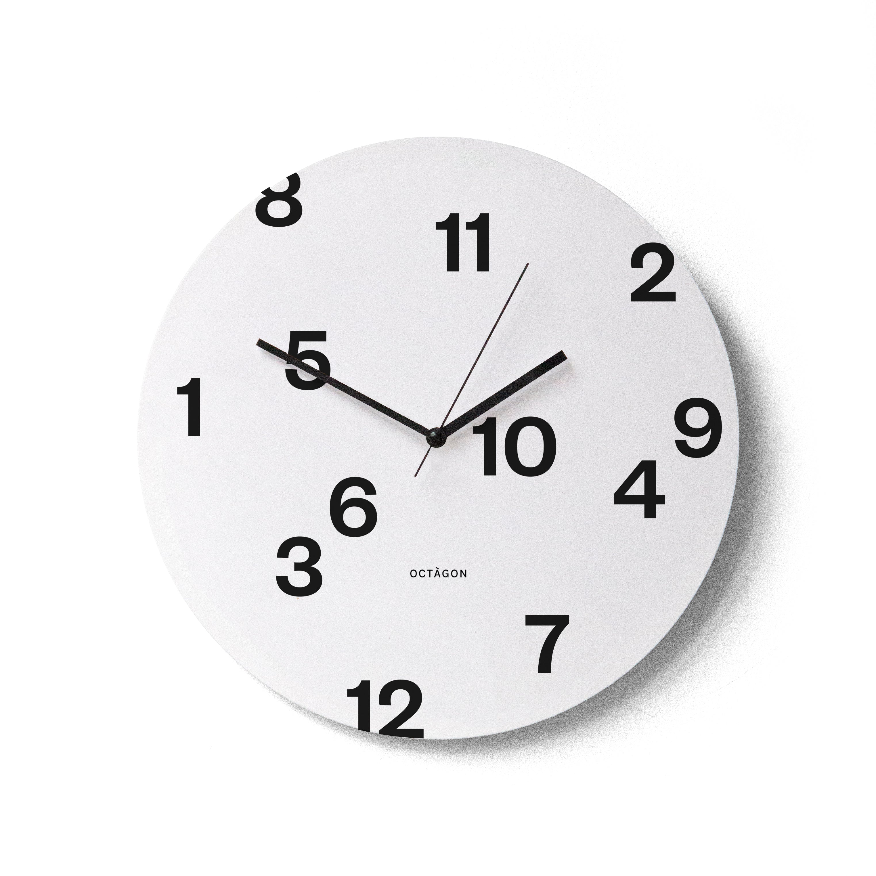 &quot;Octavi Serra&quot; wall clock. White base, typography and clock hands black colour.