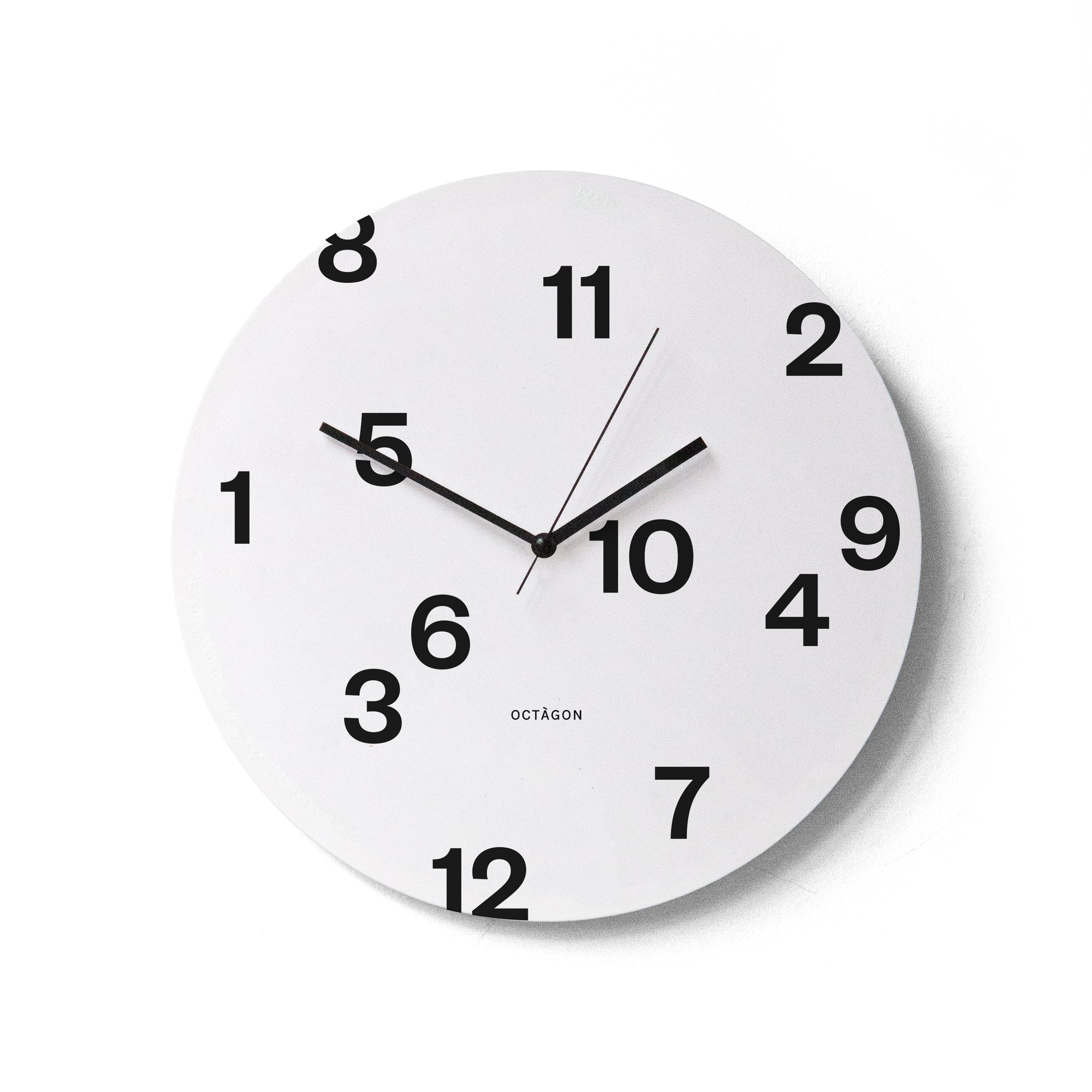 "Octavi Serra" wall clock. White base, typography and clock hands black colour.