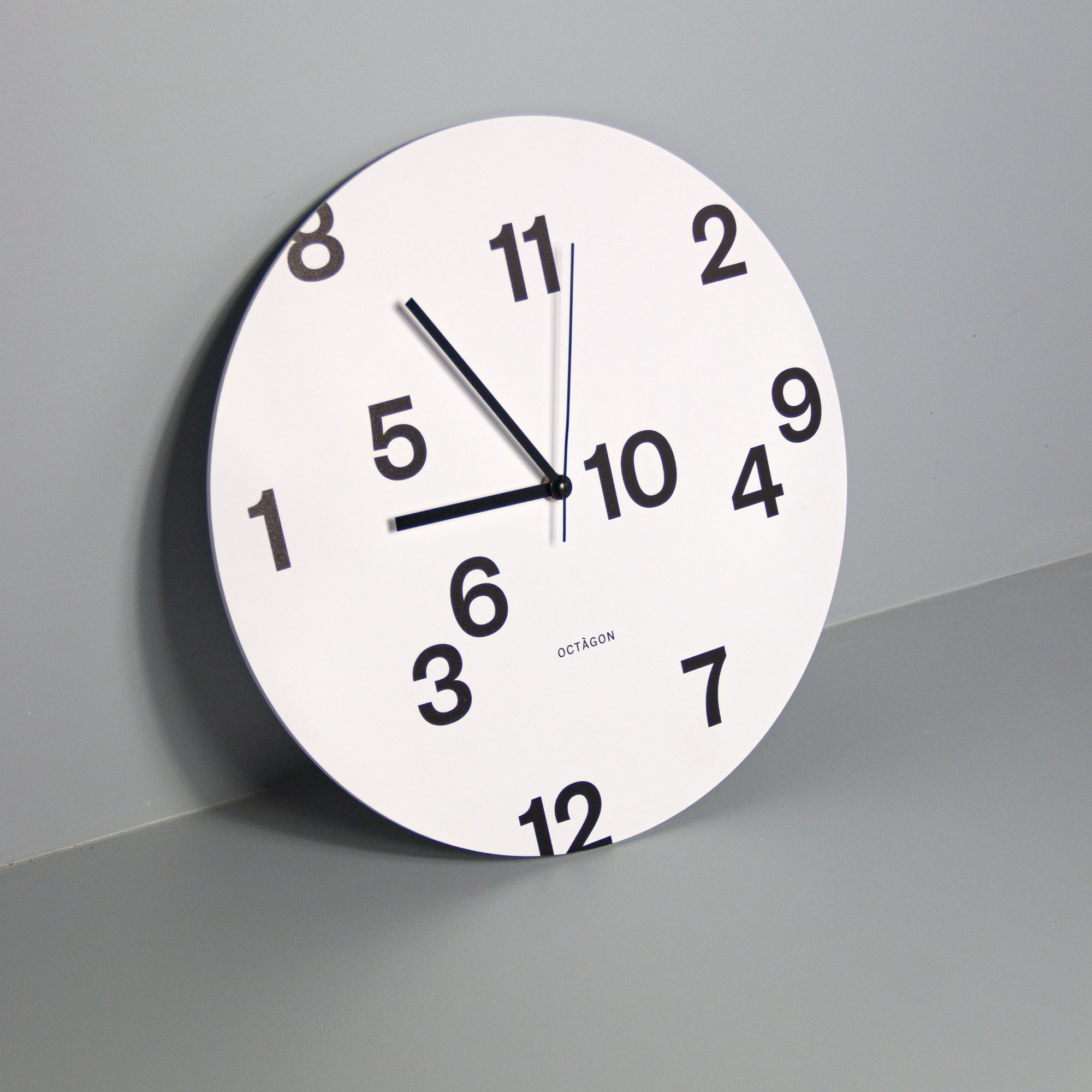 "Octavi Serra" wall clock. White base, typography and clock hands black colour.